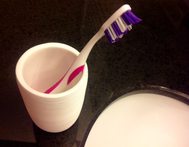 toothbrush in cup beside bathroom sink
